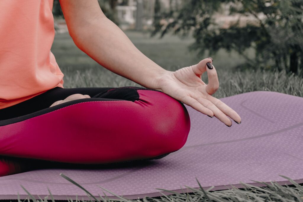 Close-up of a person meditating outdoors on a yoga mat, focusing on tranquility and mindfulness.