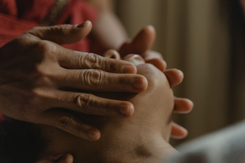 Close-up of hands performing a soothing facial massage for relaxation and wellness.