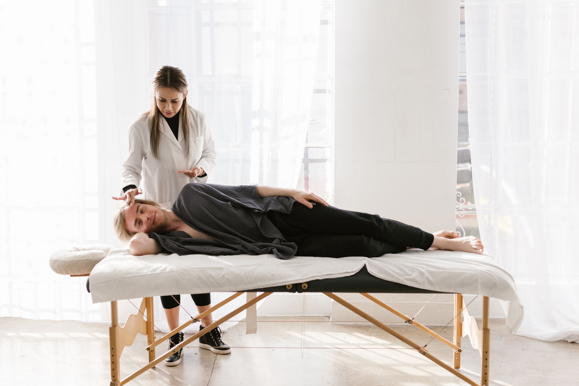 Young woman therapist provides relaxing massage therapy to a male client indoors.